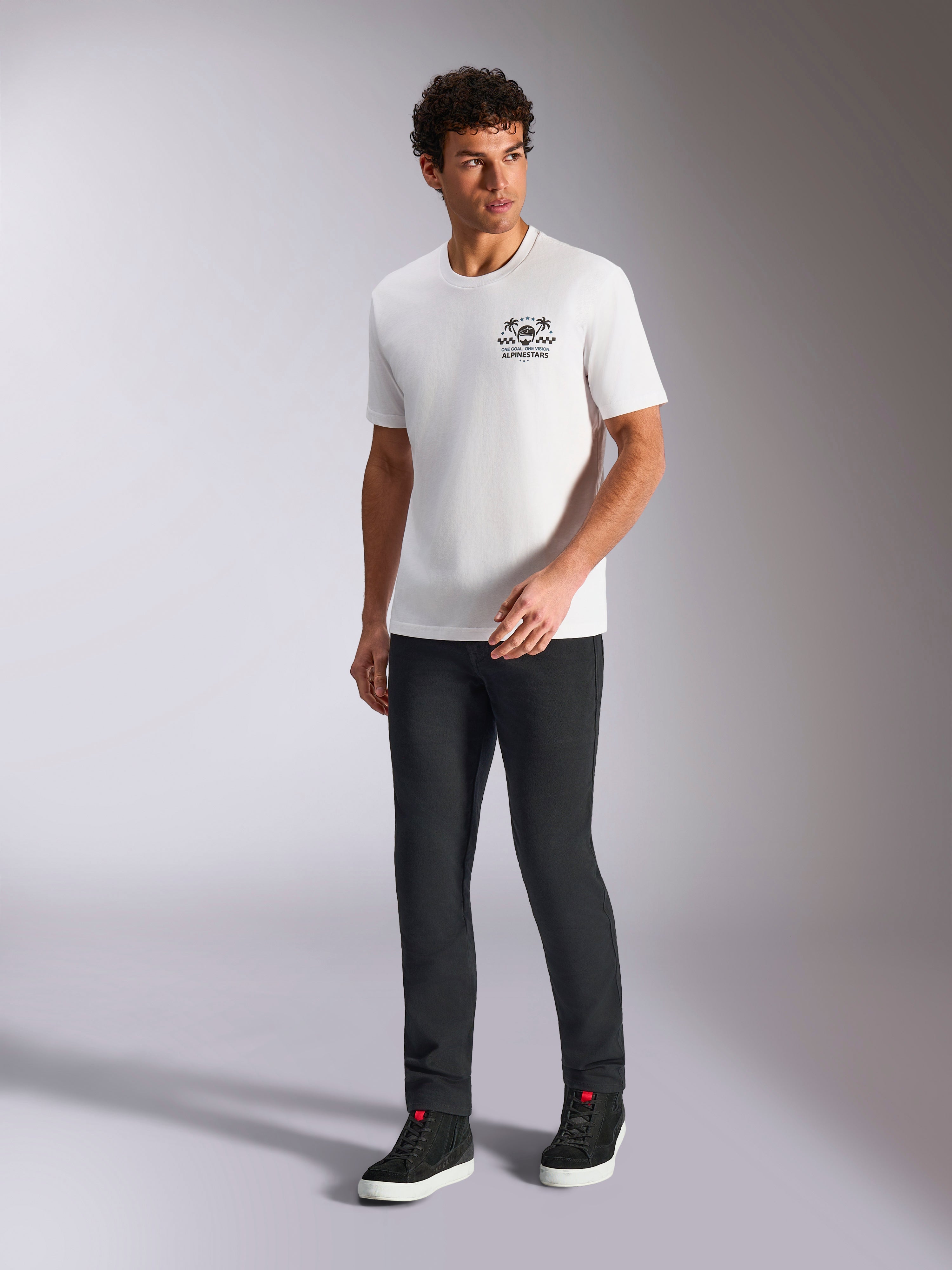 Alpinestars Order CSF Tee, T-shirt met korte mouwen, wit, logo met helm en palmbomen, gedragen met zwarte broek en hoge sneakers, casual motorsport streetwear