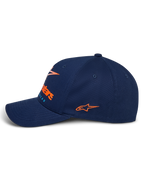 Alpinestars Instinct pet, marineblauwe sportpet, zijaanzicht met gebogen klep, oranje geborduurd logo op de zijkant, logo op de voorkant met oranje kleurverloopprint, gestructureerde bovenkant van twillstof