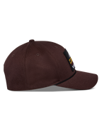 Alpinestars Matrix Snapback pet, donkerbruin, zijaanzicht met gebogen klep, gestructureerde kroon en logopatch aan de voorzijde met touwdetail, casual motorsport-geïnspireerde hoofdbedekking