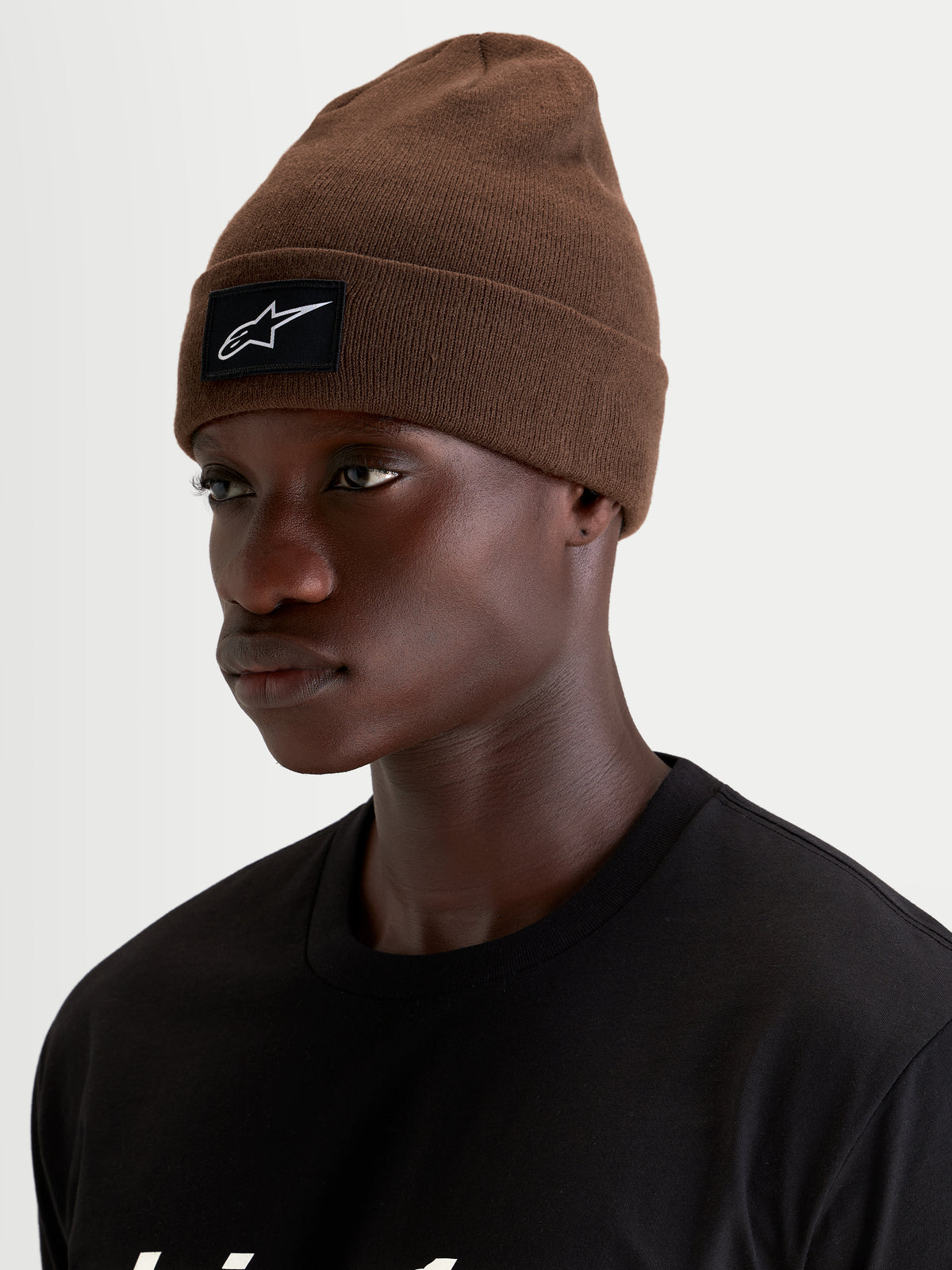 Alpinestars Augment Cuff Beanie, sportswear knit hat, brown, featuring a black and white woven Alpinestars logo patch on the cuff worn by a model