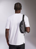 Sac banane Alpinestars Only Linear, noir avec logo Alpinestars blanc, porté en bandoulière sur un t-shirt blanc, accessoire streetwear décontracté inspiré du sport automobile