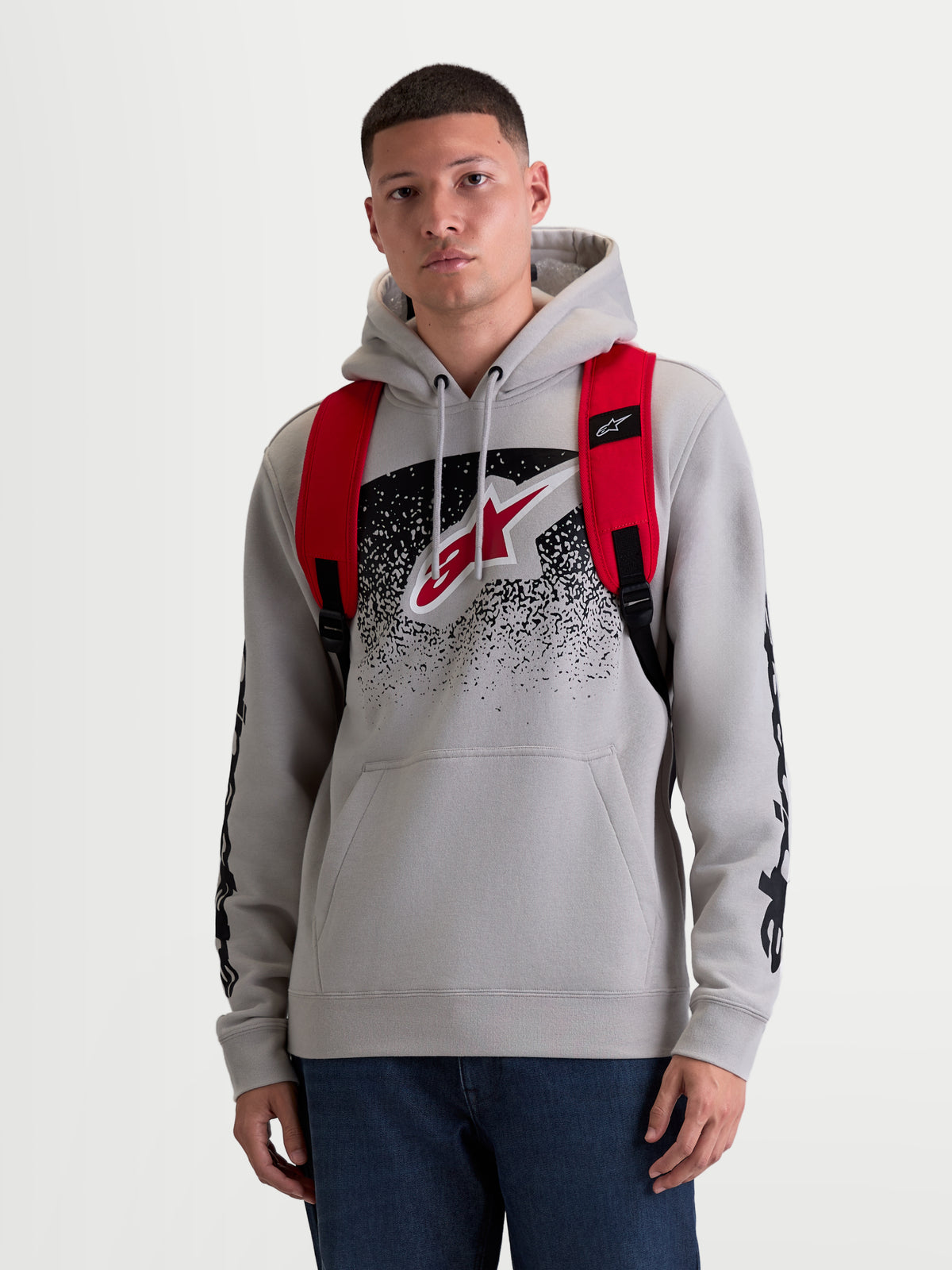 Alpinestars GFX Boss Rucksack, urbaner Sport-Tagesrucksack für Herren und Damen, Rot und Schwarz, strapazierfähiges 600D Polyester, Vorderansicht am Modell mit verstellbaren Air-Mesh-Schultergurten und erhabenem Silikon-Branding, 20L Kapazität.