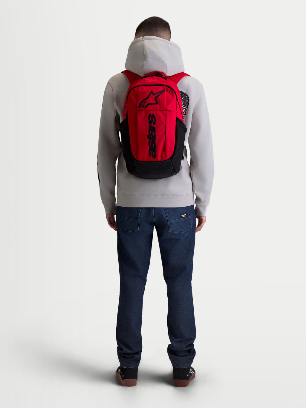 Alpinestars GFX Boss rugzak, 20L urban sportswear dagrugzak, rood en zwart, achteraanzicht op model, duurzame 600D polyester constructie, interne laptophoes en gewatteerde luchtmesh schouderbanden met verhoogde siliconen branding.