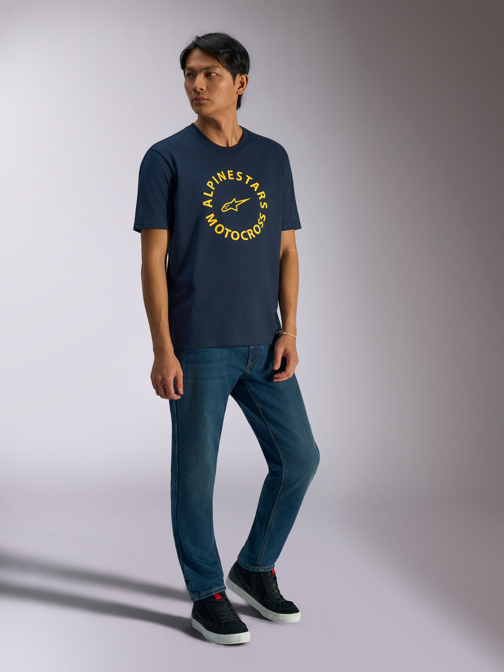 Alpinestars MX CSF Tee, T-shirt met korte mouwen, navy, gele ronde Alpinestars Motocross-grafiek, gedragen door model met blauwe jeans en zwarte sneakers, casual motorsport streetwear