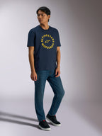 Alpinestars MX CSF Tee, T-shirt met korte mouwen, navy, gele ronde Alpinestars Motocross-grafiek, gedragen door model met blauwe jeans en zwarte sneakers, casual motorsport streetwear