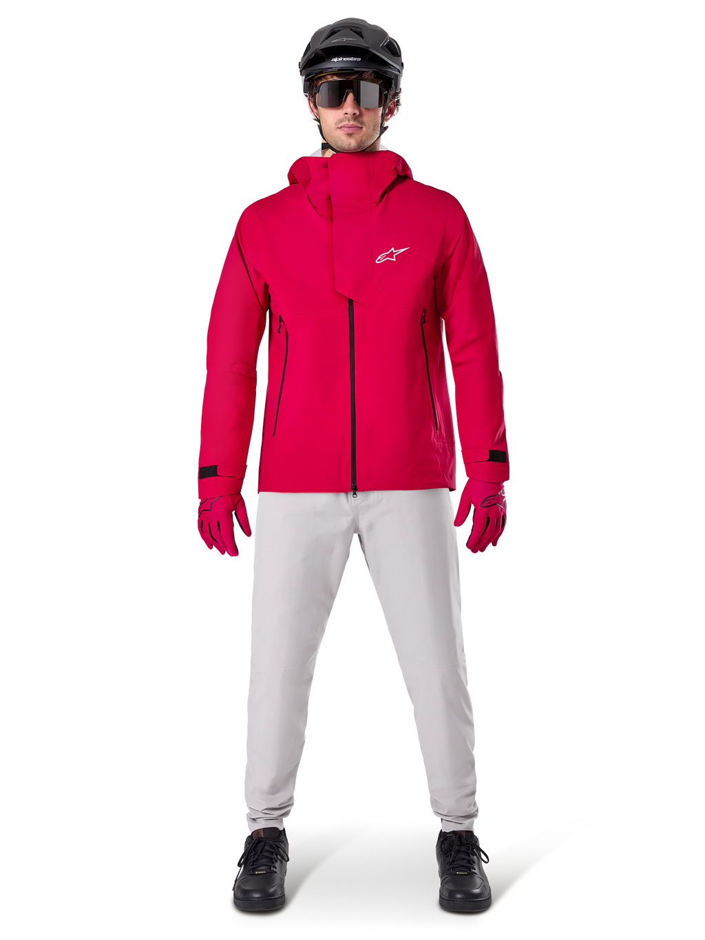 Veste imperméable Alpinestars A-Dura Elite, rouge fluo, veste technique de VTT portée avec un casque de VTT noir, des lunettes de soleil, des gants rouges assortis et un pantalon gris clair, vue d'ensemble de l'équipement de cyclisme toutes saisons