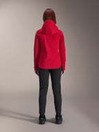 Achteraanzicht van een vrouw die de Alpinestars Stella A-Dura Elite Waterproof Jacket in Red Fluo draagt, gecombineerd met een zwarte broek en schoenen, voorzien van een beschermende capuchon en een verlengde achterzoom voor mountainbiken.