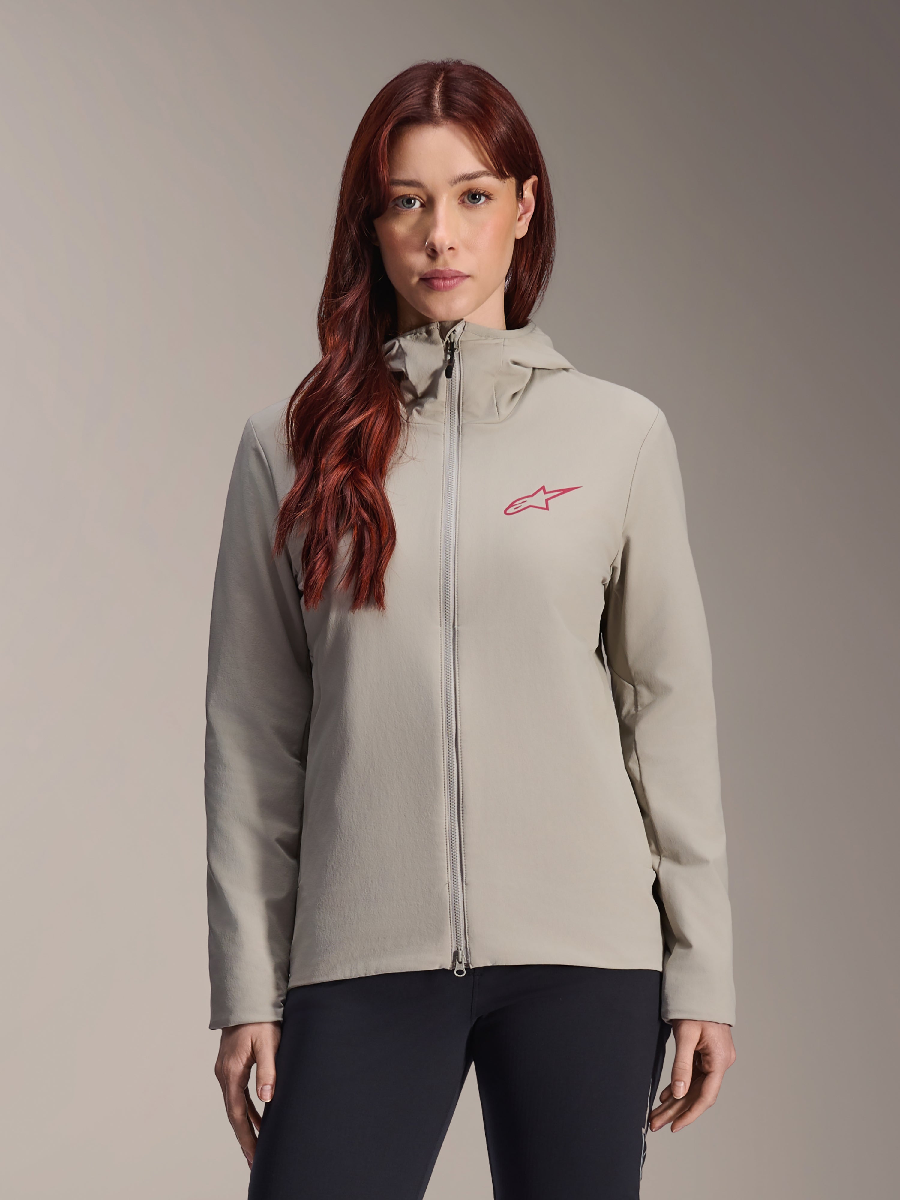 Alpinestars Stella A-Dura Thermal Jacket pour femme, gris titane, veste thermique zippée à capuche avec logo étoile rouge sur la poitrine, associée à un pantalon noir, portrait de studio lifestyle