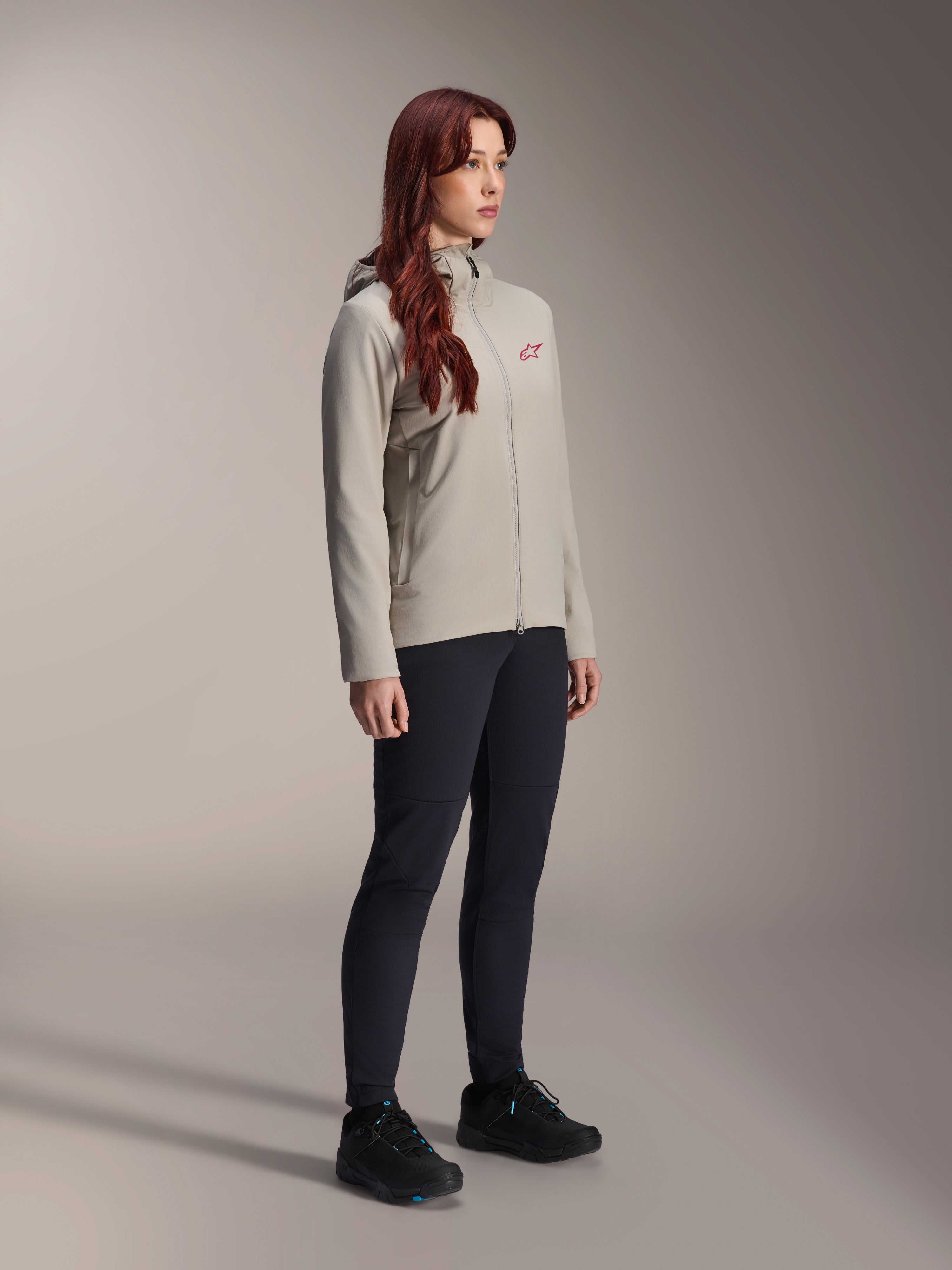 Veste thermique Alpinestars Stella A-Dura, gris titane, veste de cyclisme thermique pour femme avec un logo étoile rouge sur la poitrine, portée avec un pantalon technique noir et des chaussures de VTT noires, photo en studio pour vêtements de cyclisme