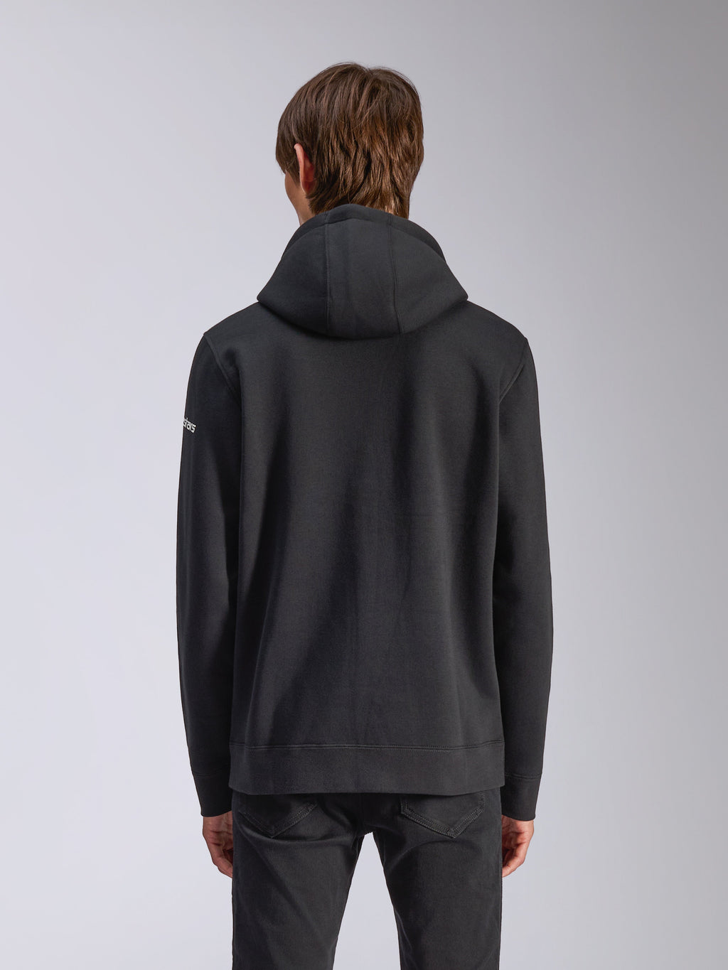 Sweat à capuche Frontal Alpinestars, noir, vue de dos d'un sweat-shirt à capuche décontracté, avec capuche doublée, ourlet côtelé et logo wordmark blanc sur la manche, streetwear inspiré des sports mécaniques.