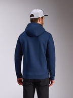 Alpinestars Frontal Hoodie, marineblauwe pullover fleece, achteraanzicht van casual streetwear, gedragen met een zwarte broek en een wit-zwarte mesh pet, modern door motorsport geïnspireerd ontwerp