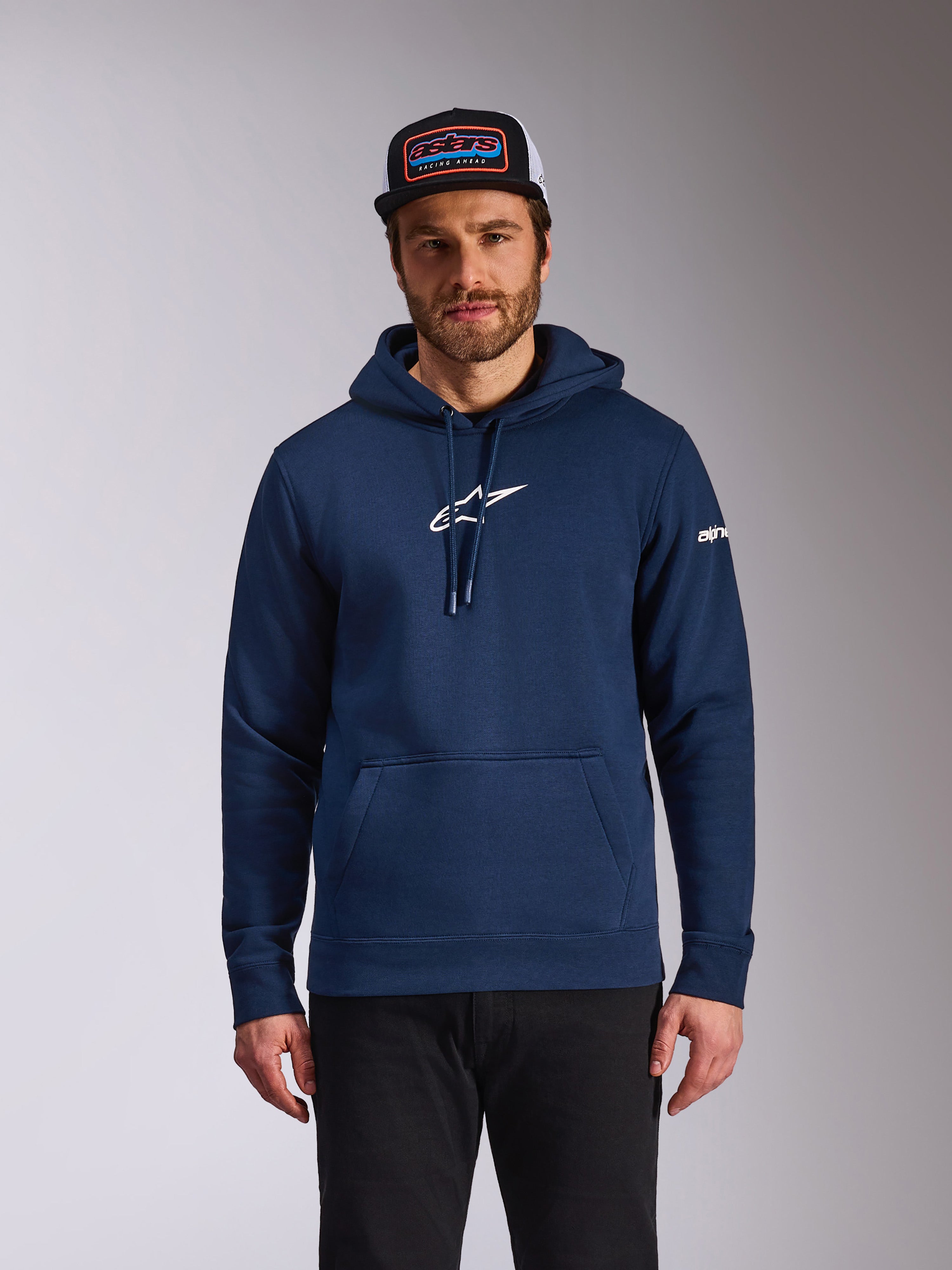 Sweat à capuche Frontal Alpinestars, streetwear décontracté inspiré du sport automobile, bleu marine avec logo Astars blanc sur la poitrine et logo écrit blanc sur la manche, poche kangourou, capuche à cordon de serrage, porté par un mannequin