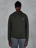 Alpinestars Essentials Ageless Hoodie, lässige Streetwear, Off-Black-Pullover mit einem kleinen weißen Alpinestars-Logo auf der Brust, getragen mit einer schwarzen Beanie, minimalistisches Design mit Kängurutasche vorne und Stone-Wash-Finish