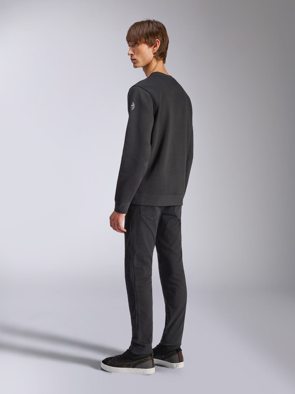 Alpinestars Bettern Crew, sweat en polaire, noir, modèle masculin vu de dos et de profil, avec poignets et ourlet côtelés et un petit logo sur la manche, streetwear décontracté d'inspiration sport mécanique
