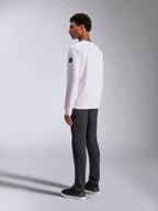 Alpinestars Bettern Crew, sweat-shirt à col rond blanc, vue de dos et de côté, logo circulaire noir sur la manche, porté avec un pantalon gris foncé et des baskets noires, style streetwear motorsport décontracté