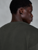 Alpinestars Essentials Ageless Crew, hochwertiges Rundhals-Sweatshirt in Off Black, Detailaufnahme des hinteren Halsausschnitts und Schulterbereichs, Kompaktfleece-Textur mit Stone-Washed-Effekt, lässige motorsport-inspirierte Streetwear