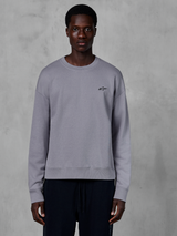 Alpinestars Essentials Ageless Crew, sweat-shirt à col rond argenté porté par un mannequin, avec un petit logo étoile noir sur la poitrine, coupe décontractée avec poignets et ourlet côtelés, style streetwear décontracté inspiré du sport automobile