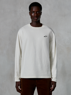 T-shirt à manches longues Alpinestars Essentials Ageless, blanc cassé, petit logo étoile noir sur la poitrine, streetwear décontracté, coupe décontractée, porté par un mannequin