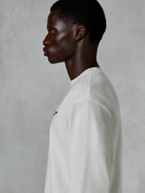 Alpinestars Essentials Ageless LS Tee, t-shirt à manches longues, blanc cassé, vue de profil d'un homme portant le t-shirt à coupe décontractée, avec un petit logo noir sur la poitrine, vêtement lifestyle décontracté d'inspiration sport automobile