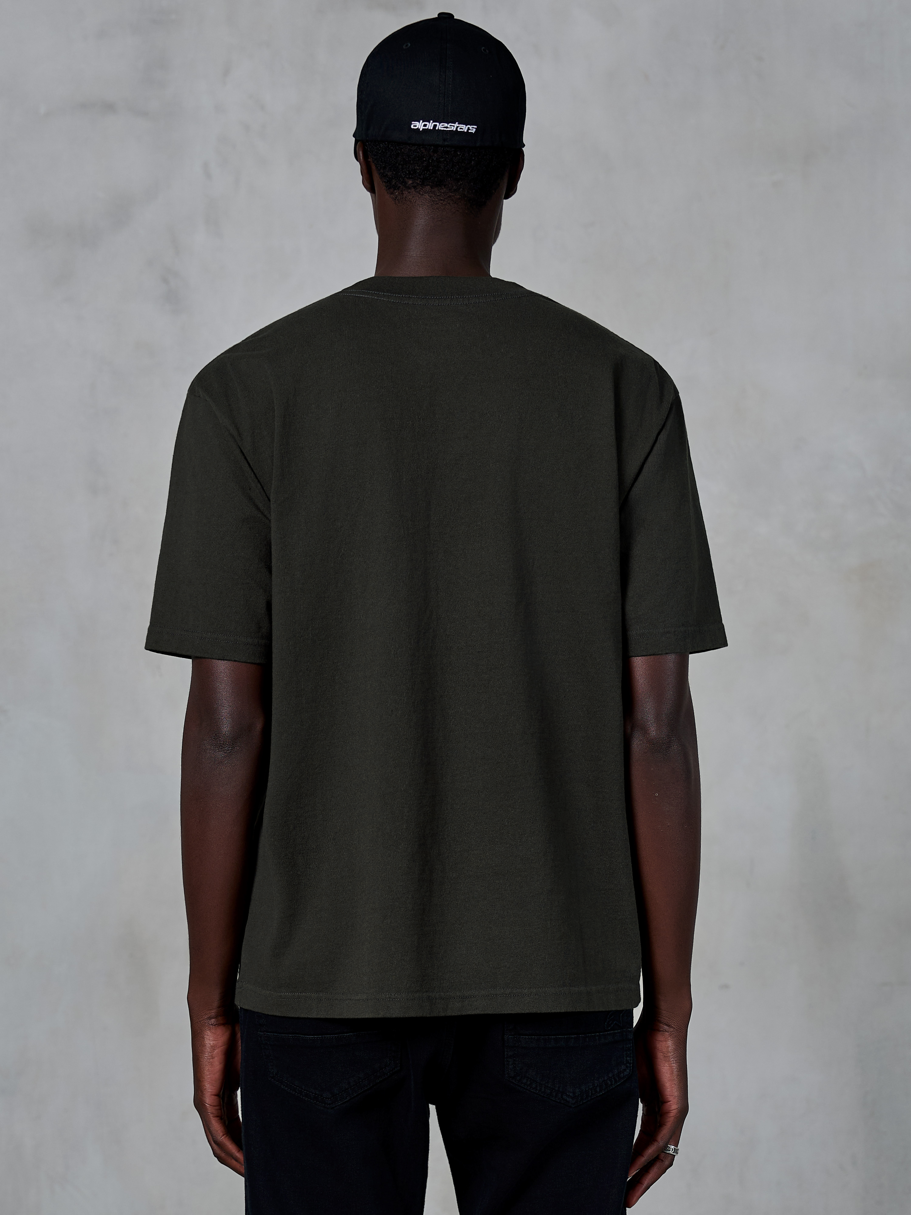 Alpinestars Essentials Ageless SS Tee, achteraanzicht van een T-shirt met korte mouwen, Off Black, biologisch katoenen jersey met een relaxte pasvorm, casual motorsport-geïnspireerde streetwear gecombineerd met een zwarte logopet
