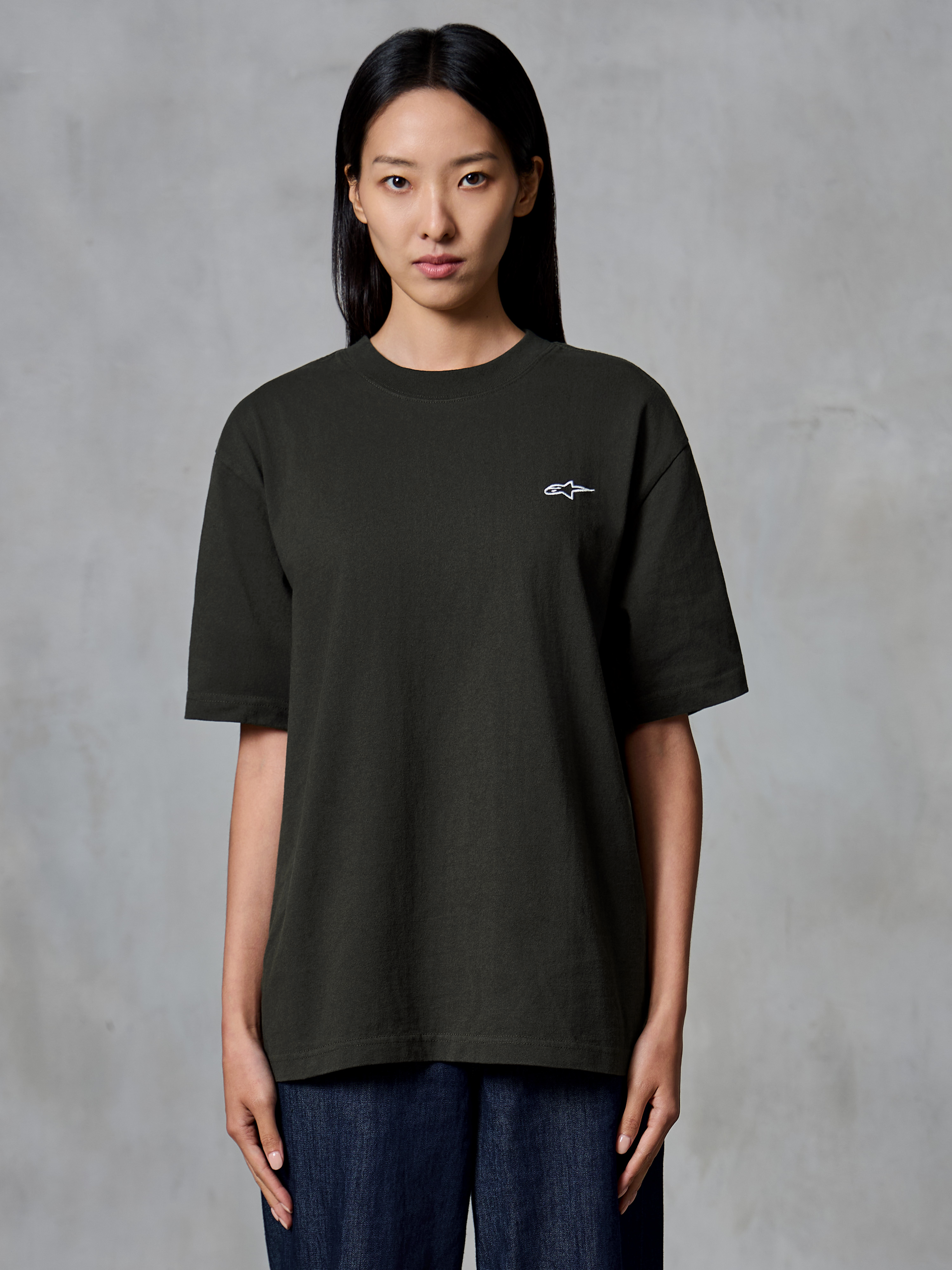 Alpinestars Essentials Ageless SS Tee, T-shirt met korte mouwen, Off Black, gedragen door een vrouwelijk model, relaxed fit met een klein wit Alpinestars-logo op de linkerborst, casual lifestyle kleding