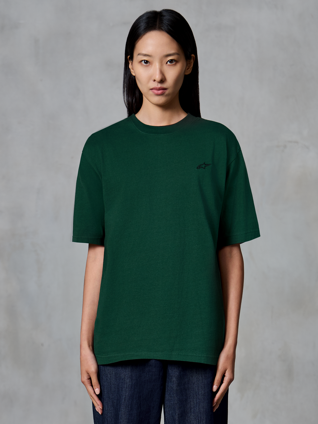 Alpinestars Essentials Ageless SS Tee, t-shirt à manches courtes, vert sapin, porté par un mannequin, avec un petit logo noir sur la poitrine, coupe décontractée, streetwear décontracté en coton biologique