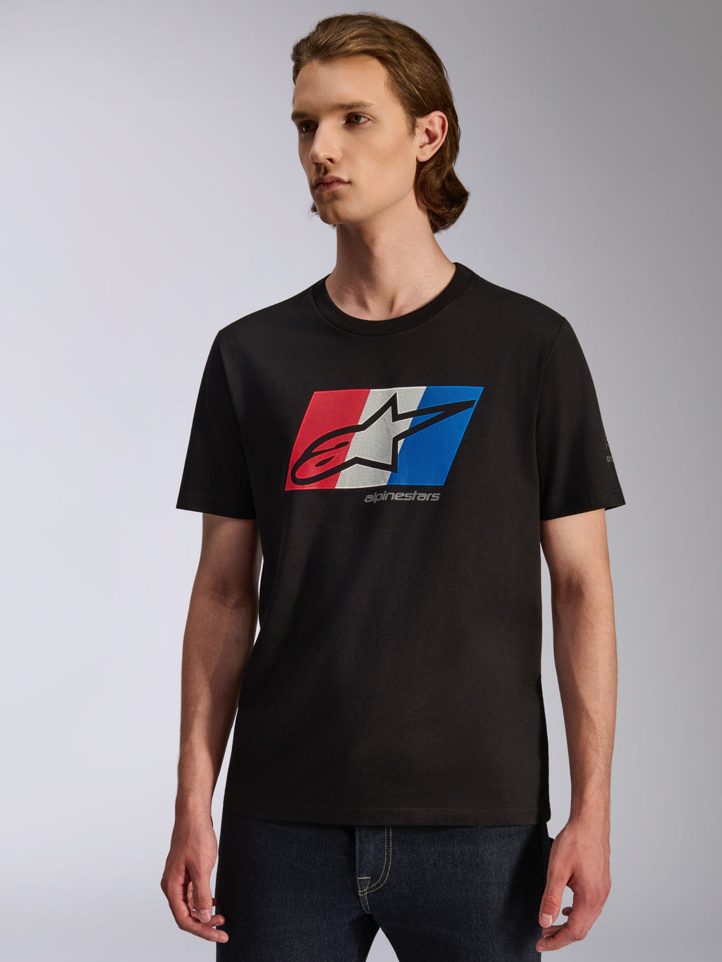 Alpinestars Global CSF Tee, T-shirt met korte mouwen, zwart met rood, wit en blauwe grafische print op de borst, Ageless shadow-logo, casual op de motorsport geïnspireerde streetwear, model draagt het T-shirt