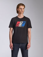 Alpinestars Global CSF Tee, T-shirt met korte mouwen, zwart, rood wit en blauw Ageless logo graphic, gedragen door mannelijk model met donkere jeans, casual motorsport streetwear