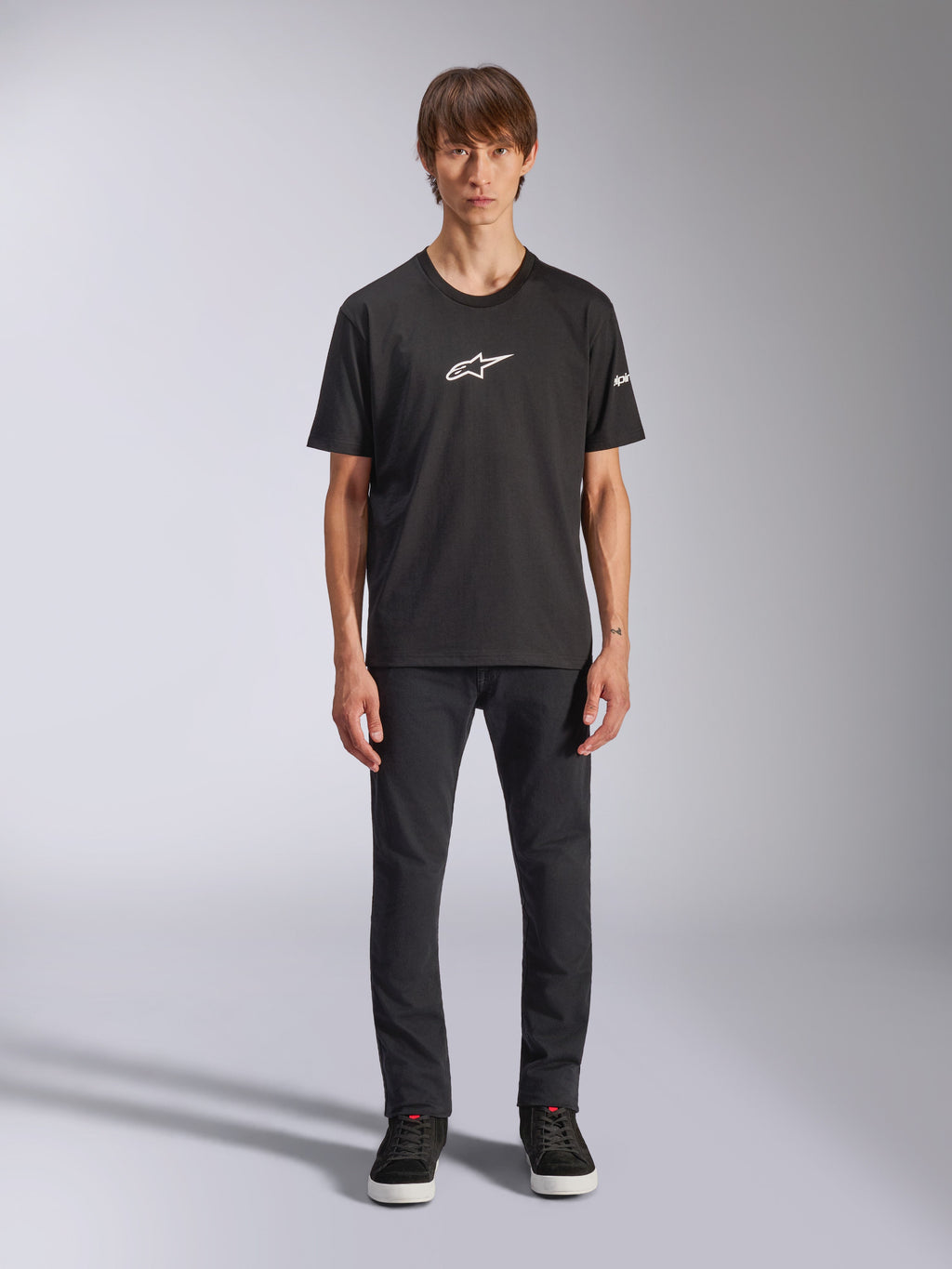 Alpinestars Frontal CSF Tee, T-shirt met korte mouwen, zwart, wit Alpinestars-logo op de borst, gedragen door model met zwarte broek en zwarte schoenen, casual performance sportkleding
