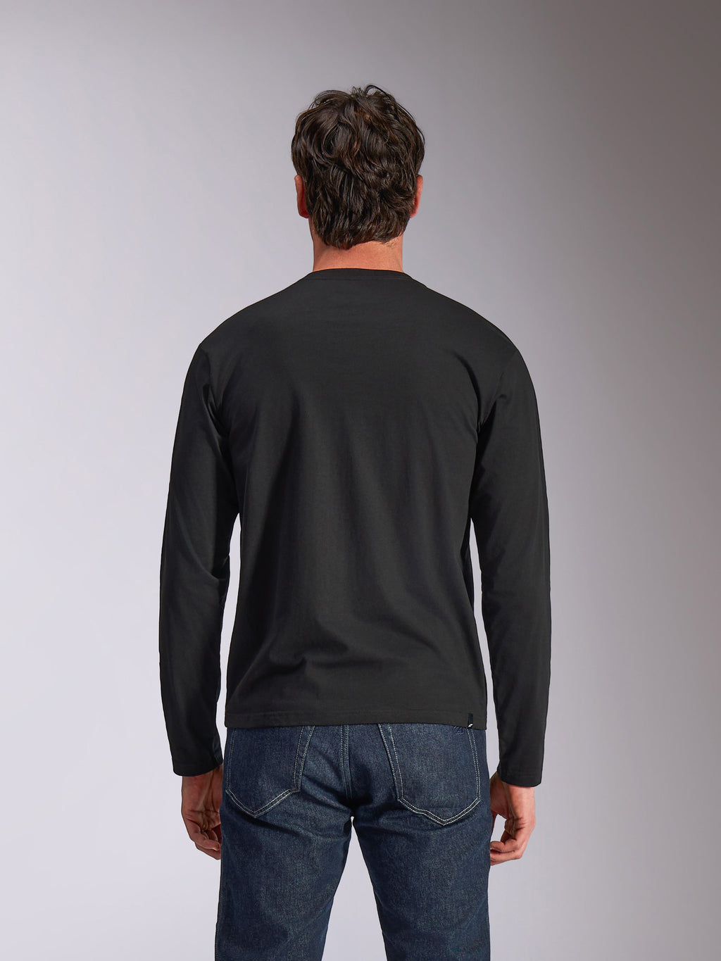 Alpinestars Trackside CSF Tee, T-shirt met lange mouwen, zwart, achteraanzicht, gedragen met een donkerblauwe spijkerbroek, casual motorsport-geïnspireerde streetwear