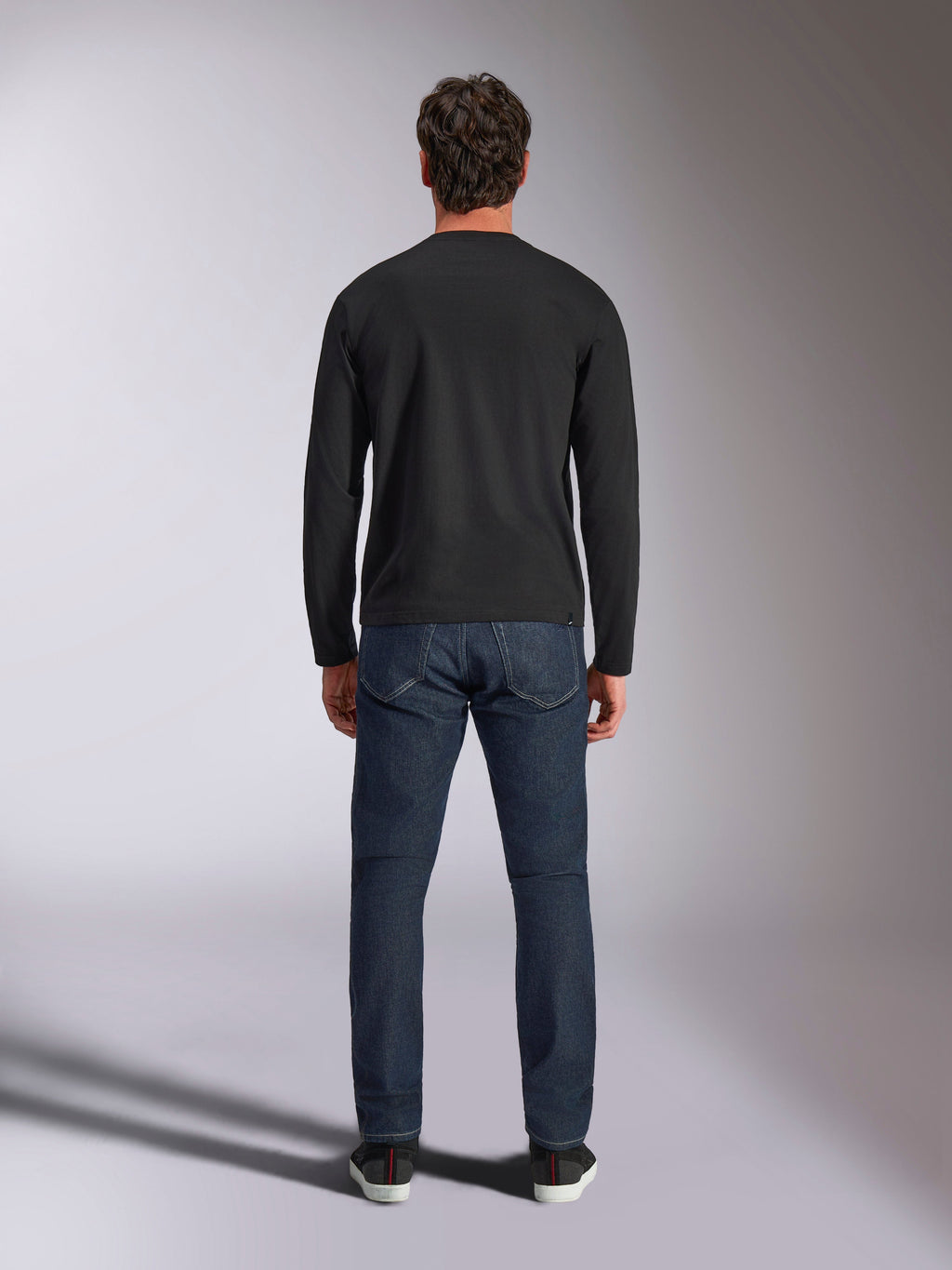 Alpinestars Trackside CSF Tee, T-shirt met lange mouwen, zwart, achteraanzicht op een model in een donkerblauwe spijkerbroek, casual motorsport streetwear