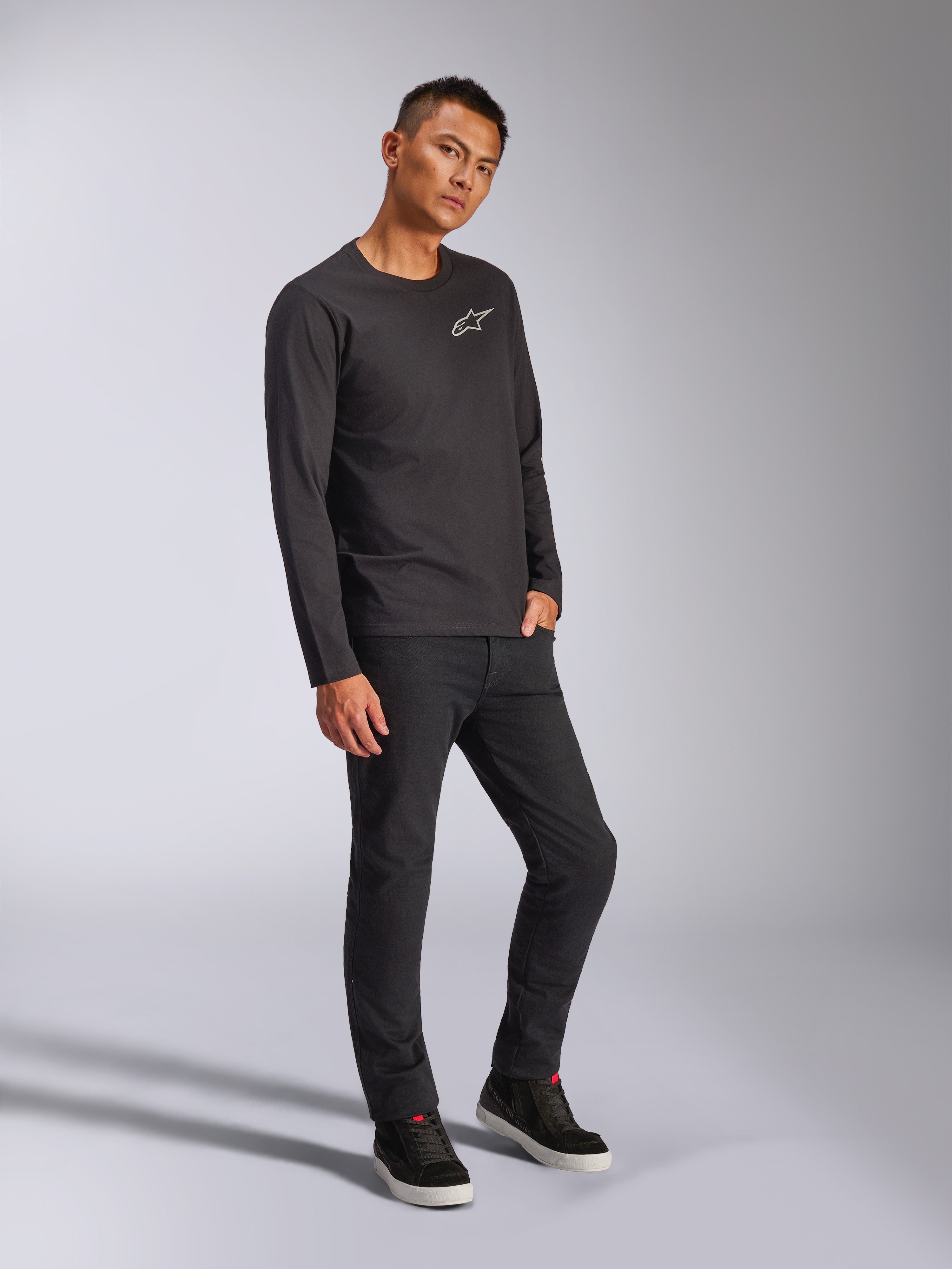Alpinestars Trackside CSF Tee, T-shirt met lange mouwen, zwart, wit Astars-logo op de borst, gedragen door model met zwarte broek en sneakers, casual op motorsport geïnspireerde streetwear