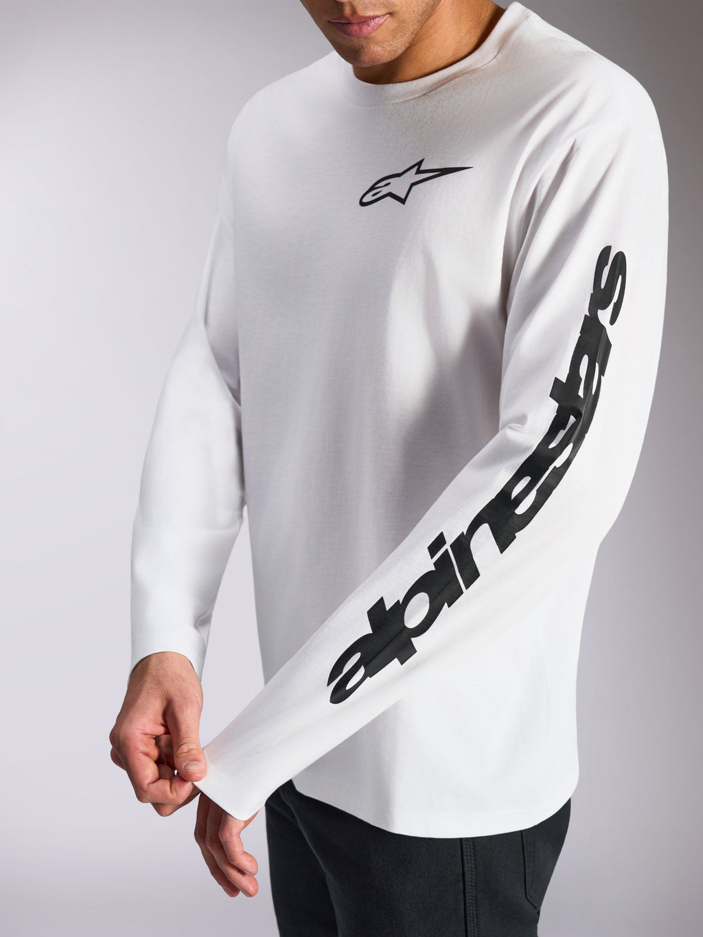 Alpinestars Trackside CSF Tee, T-shirt met lange mouwen, wit met zwart, klein zwart sterlogo op de borst en opvallend woordmerk op de mouw, casual streetwear geïnspireerd op de motorsport