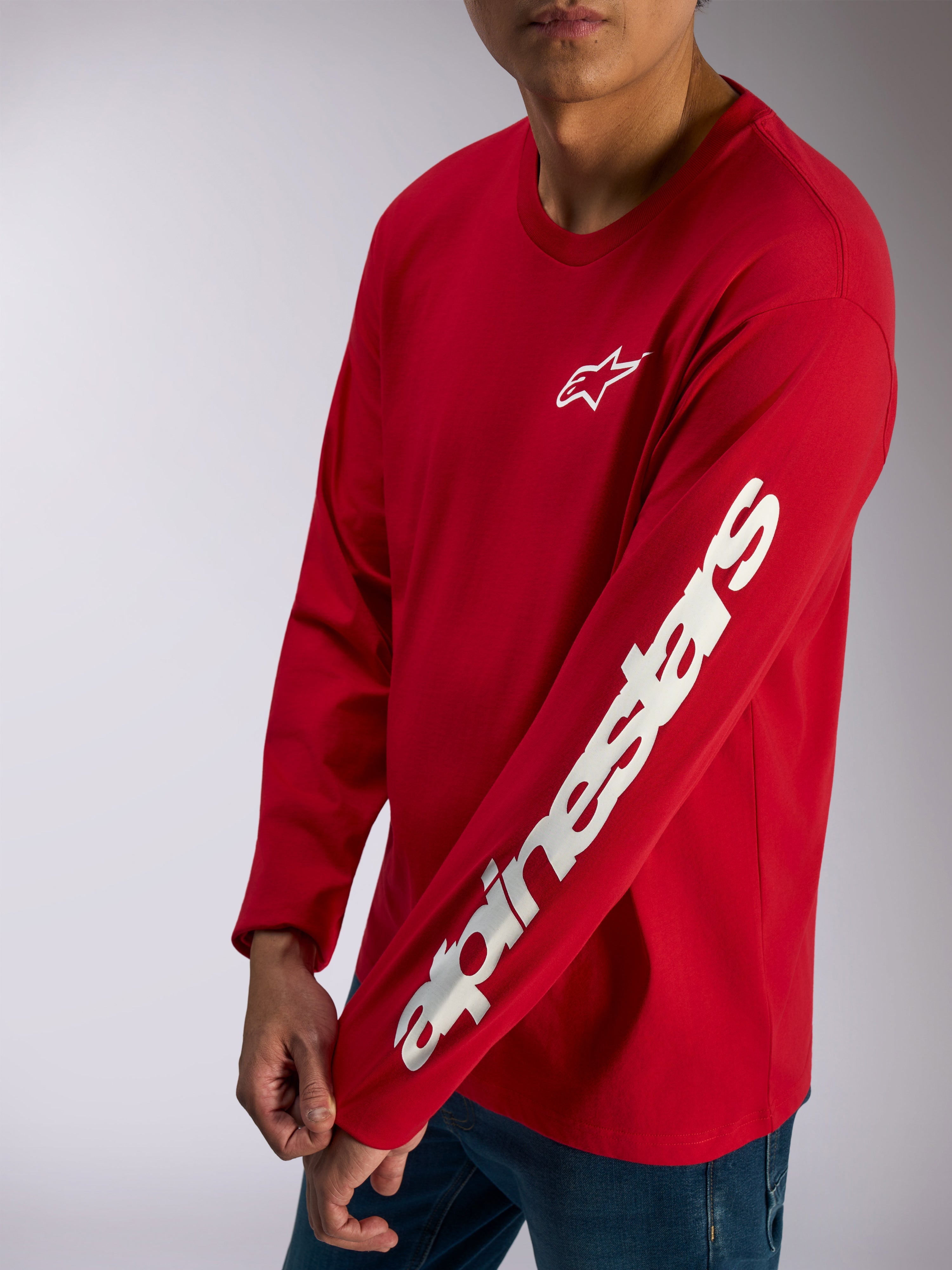Alpinestars Trackside CSF Tee, t-shirt met lange mouwen, rood, wit Alpinestars-logo op de borst en opvallend woordmerk op de mouw, casual motorsport streetwear gedragen met een blauwe jeans