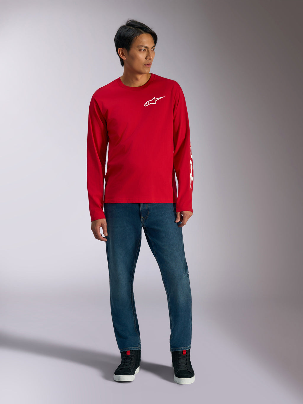 Alpinestars Trackside CSF Tee, T-shirt met lange mouwen, rood met wit Alpinestars-logo, lifestyle-foto gedragen met blauwe jeans en zwarte sneakers, casual op de motorsport geïnspireerde sportkleding