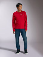 Alpinestars Trackside CSF Tee, T-shirt met lange mouwen, rood met wit Alpinestars-logo, lifestyle-foto gedragen met blauwe jeans en zwarte sneakers, casual op de motorsport geïnspireerde sportkleding