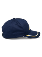 Casquette Snapback Ascension Alpinestars, vue de côté, bleu marine avec double passepoil sutache doré et blanc sur la visière courbée, couronne structurée, accessoire casual motorsport