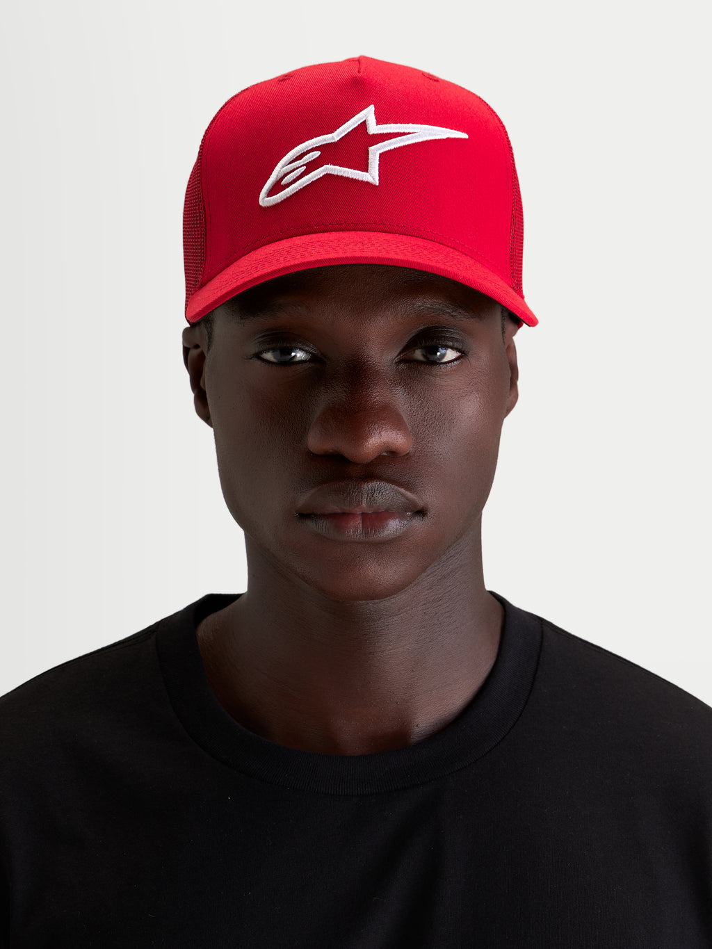 Alpinestars Ageless Snapback Kappe, rote Sportswear-Kappe getragen von einem Model, mit weißer 3D-Stickerei des Astars-Logos, gebogenem Schirm und strukturierter Baumwoll-Twill-Konstruktion
