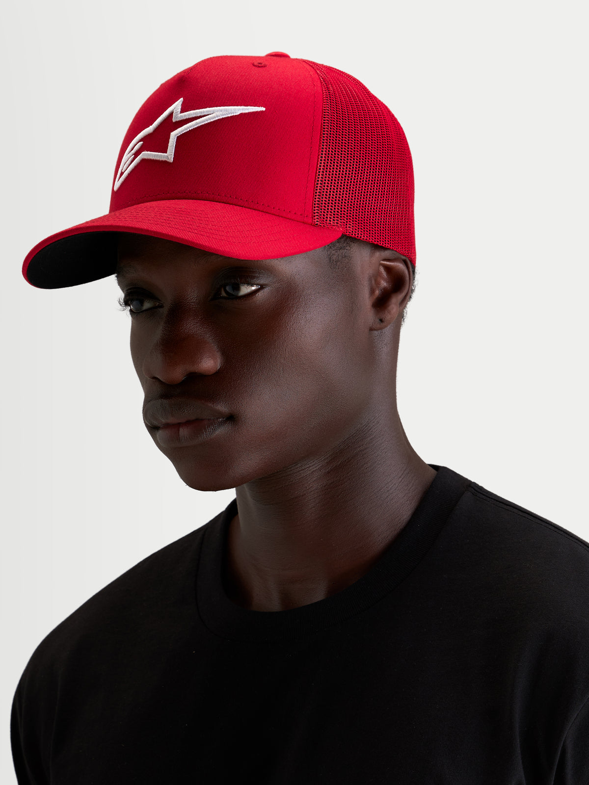Alpinestars Ageless Snapback pet, sportswear pet gedragen door een model, rood en wit met een opvallend geborduurd 3D Astar-logo en gebogen klep, katoenen keperstof en mesh constructie