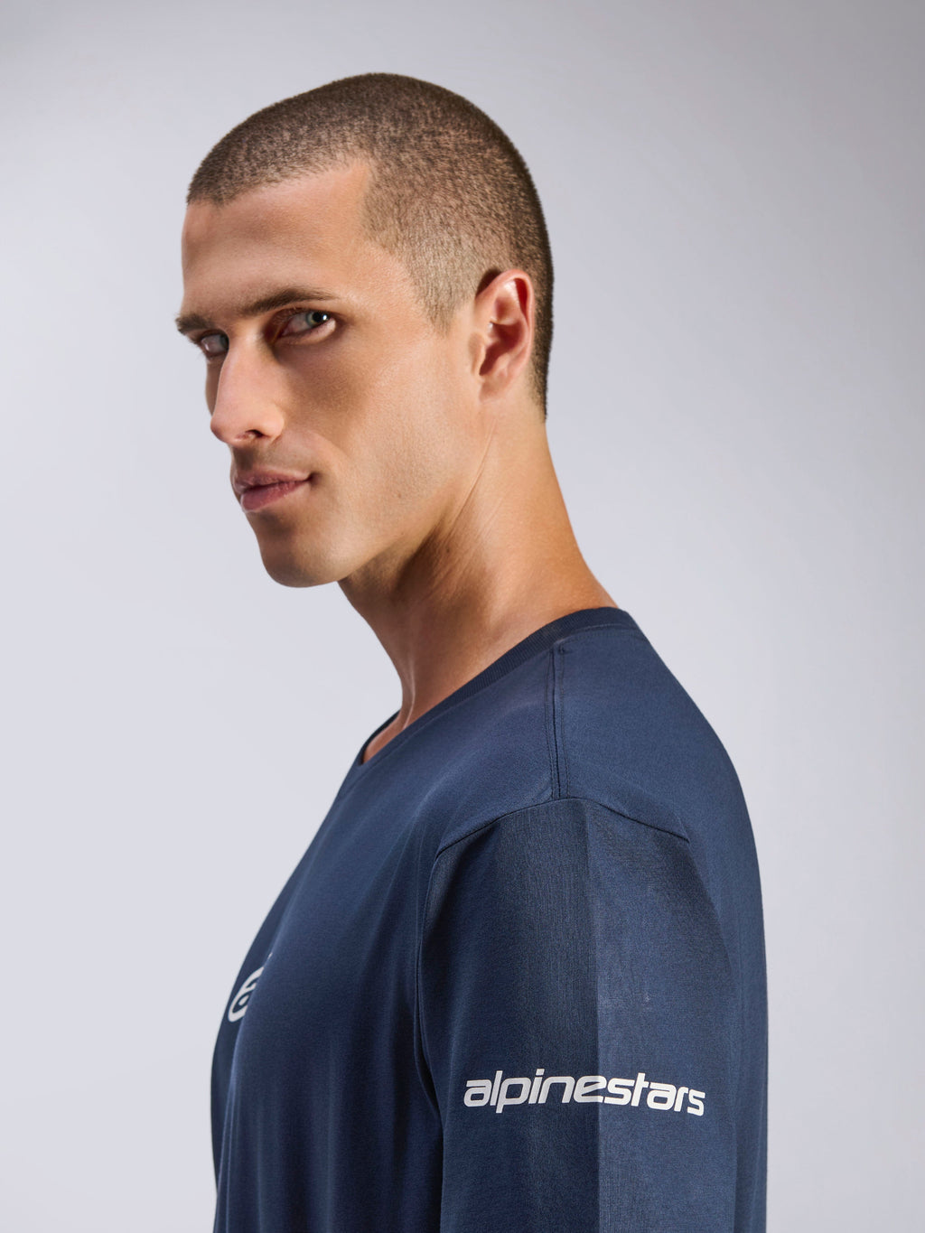 Alpinestars Frontal CSF Tee, T-shirt met korte mouwen, navy blauw, zijprofiel van mannelijk model, wit Alpinestars-logo op de mouw, performance vochtafvoerende stof, casual motorsport lifestyle