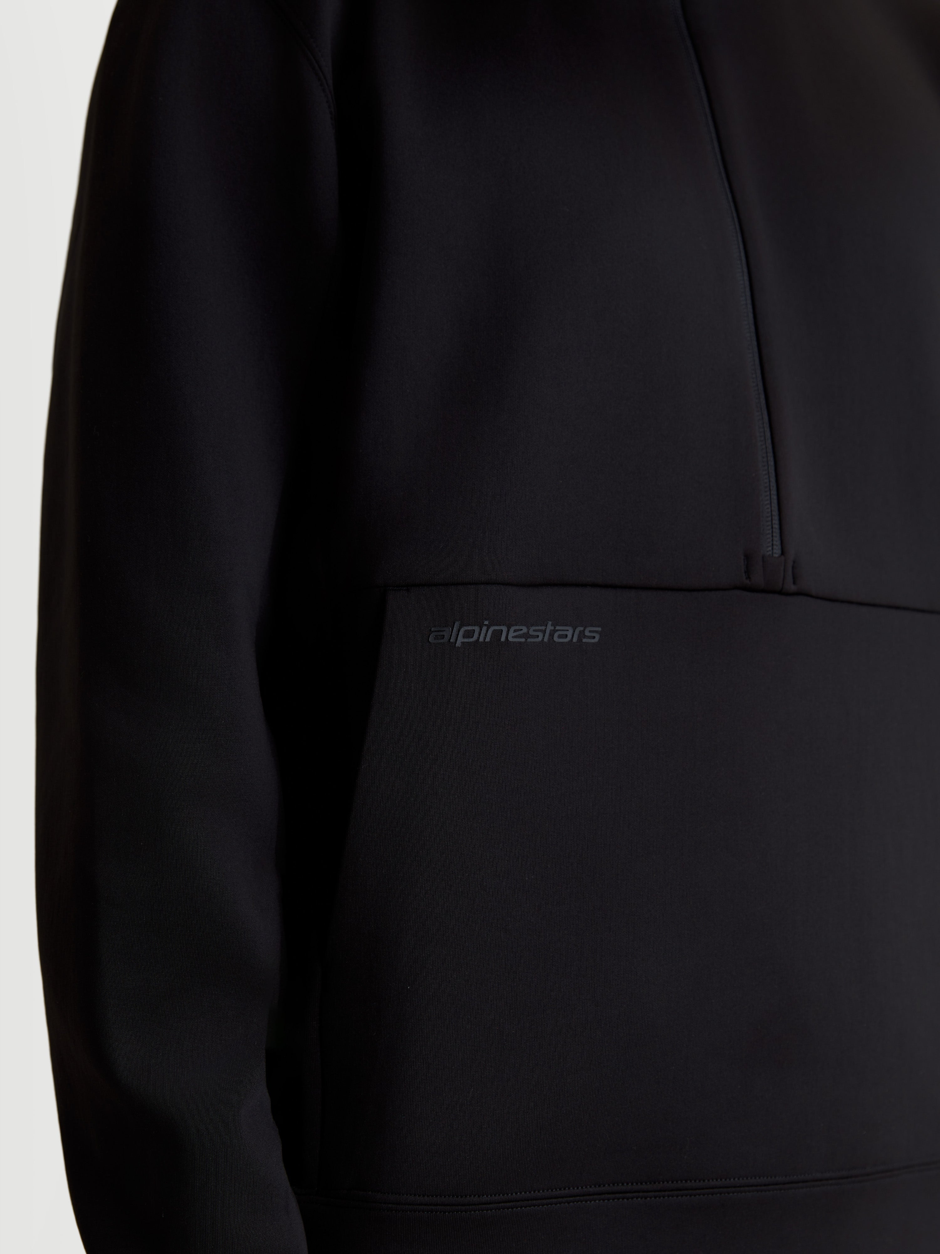 Alpinestars Sweat Half-Zip Apera, pull sportswear noir, gros plan montrant le logo HD ton sur ton sur la poche kangourou et le design demi-zippé, polaire tri-mélange premium.