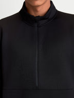 Alpinestars Sweat Half-Zip Apera, pull sportswear noir, gros plan sur la fermeture demi-zippée et le col montant, porté par un modèle, en polaire tri-mélange avec logo Alpinestars ton sur ton pour un style inspiré du sport automobile.