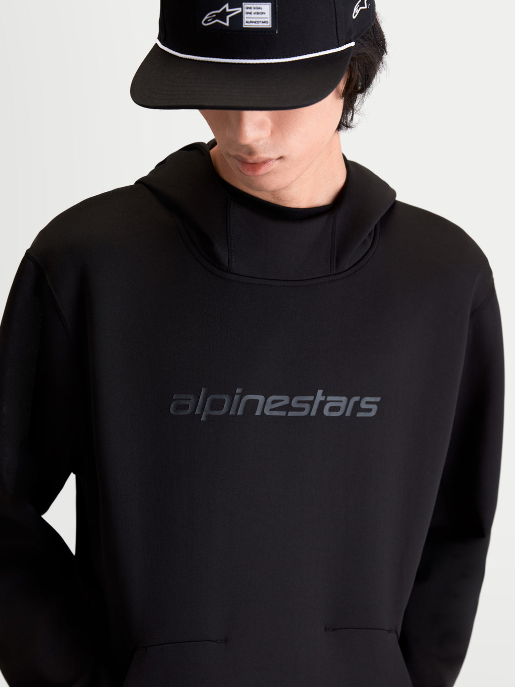 Alpinestars Datrix Hoodie, sweat à capuche sportswear pour homme, noir, polaire double face tri-mélange avec logo Alpinestars HD ton sur ton sur la poitrine, capuche doublée en mesh et poche avec détail de pli, vue de face sur modèle.