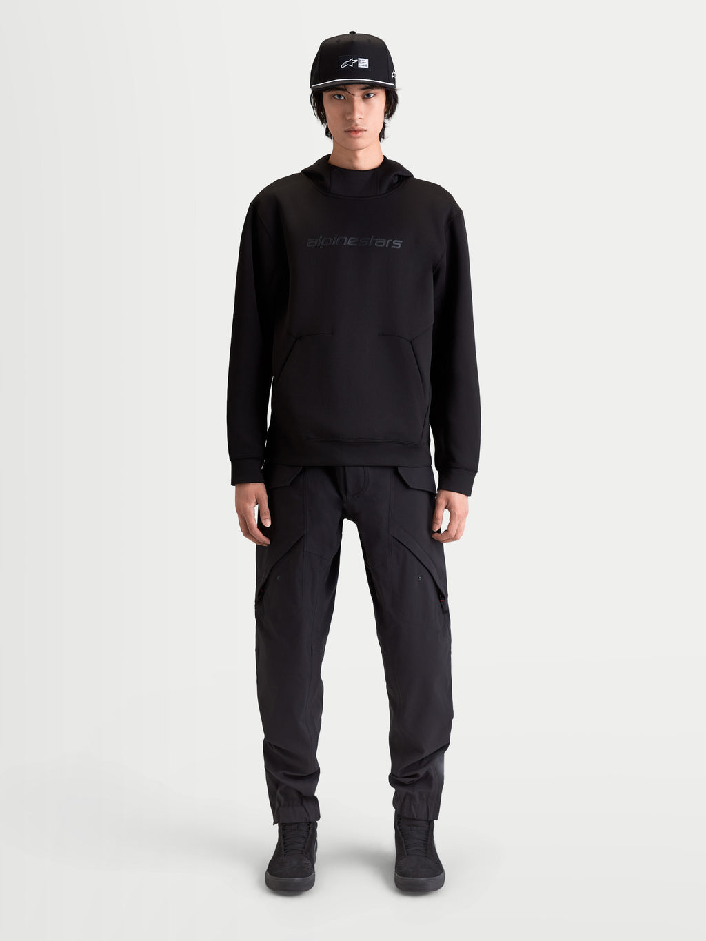 Alpinestars Sweat À Capuche Datrix, sweat à capuche sportswear pour homme, noir, avec marquage HD ton sur ton, polaire double face et poche avec détail de pli, porté par un modèle.