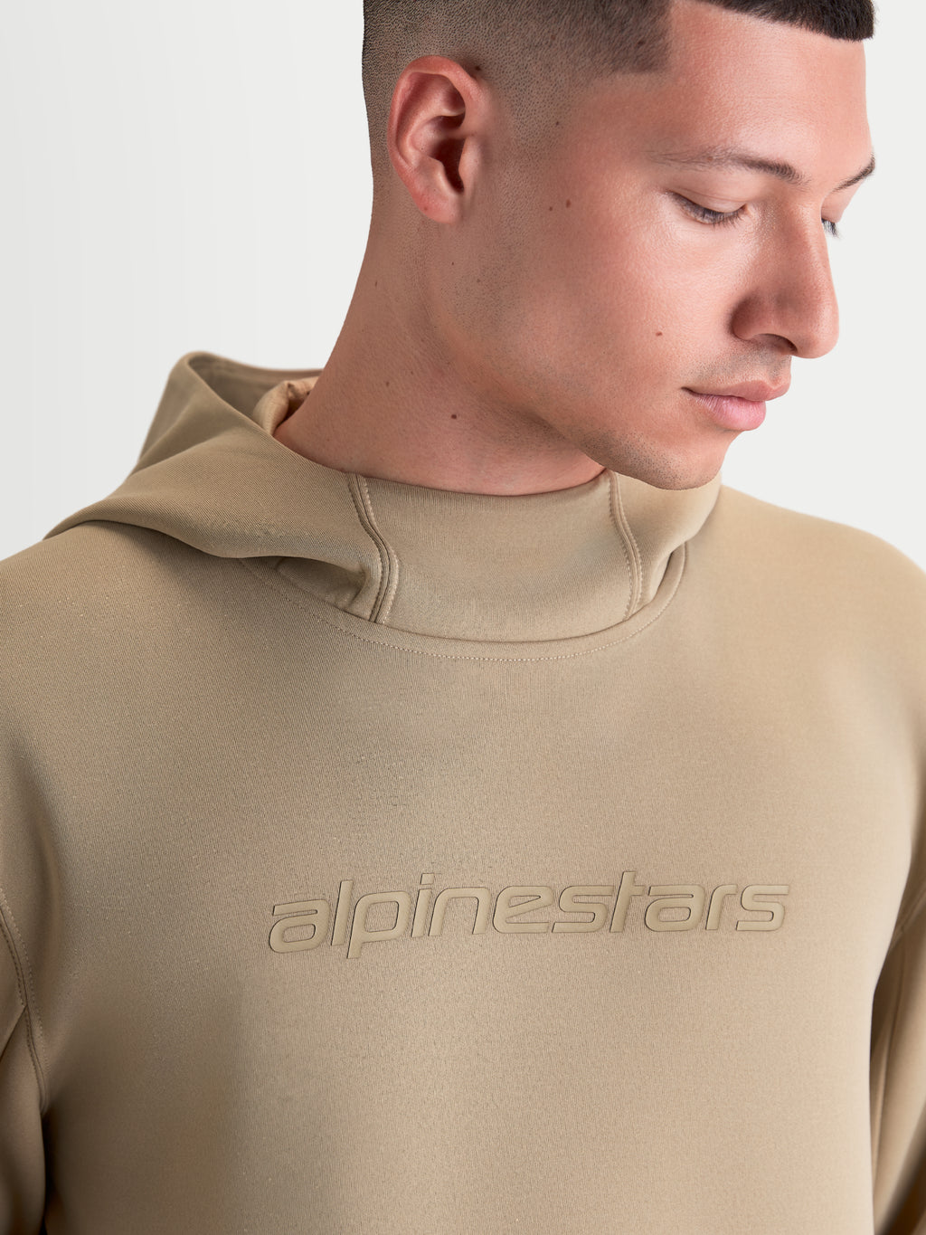Alpinestars Sweat à capuche Datrix, sweat de sportswear pour homme et femme, marron, avec logo Alpinestars ton sur ton et capuche doublée en mesh, gros plan sur mannequin montrant la construction en polaire premium