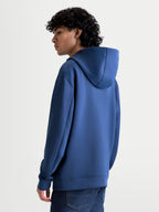 Alpinestars sweat à capuche Datrix, pull de sportswear pour un style décontracté inspiré du sport automobile, bleu acier, construction en polaire double face avec capuche doublée en mesh, vue de dos et de profil sur un modèle.