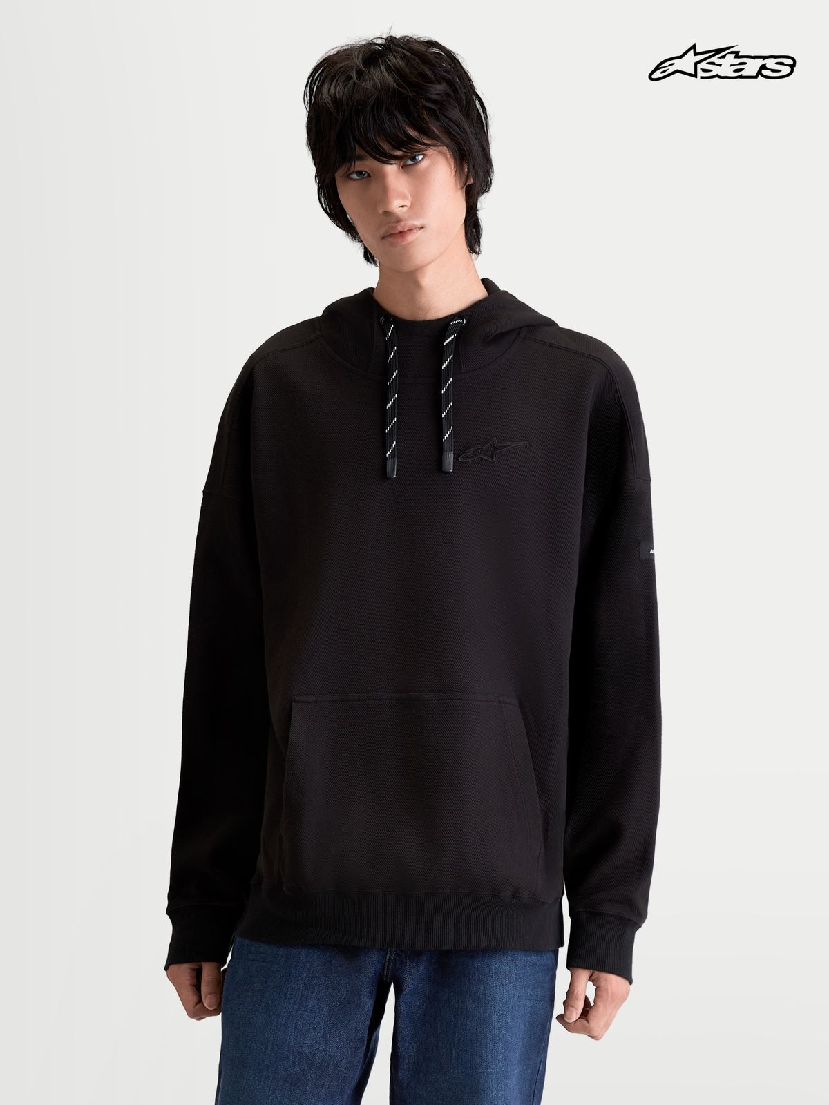 Sweat à Capuche Textured Oversize Camino d'Alpinestars, sweat à capuche sportswear noir pour homme, polaire texturée en maille sergée avec poche kangourou et col haut, porté par un modèle
