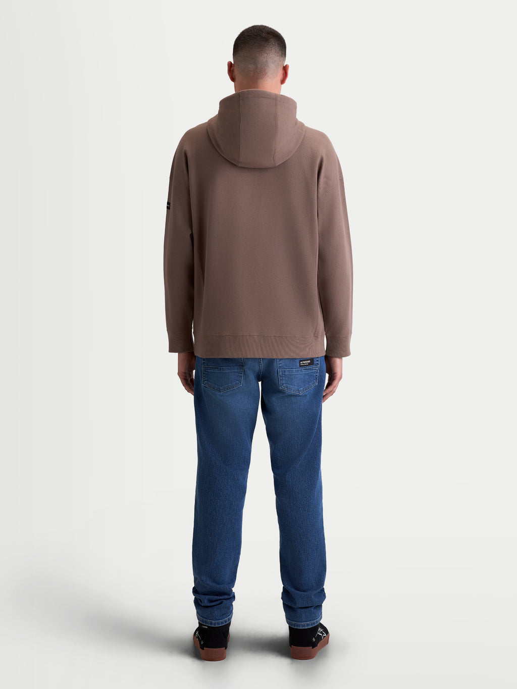 Alpinestars Sweat à capuche Textured Oversized Camino, sweat à capuche sportswear pour homme, marron, vue de dos sur modèle, confection en polaire texturée en maille sergée avec poignets et ourlet côtelés.