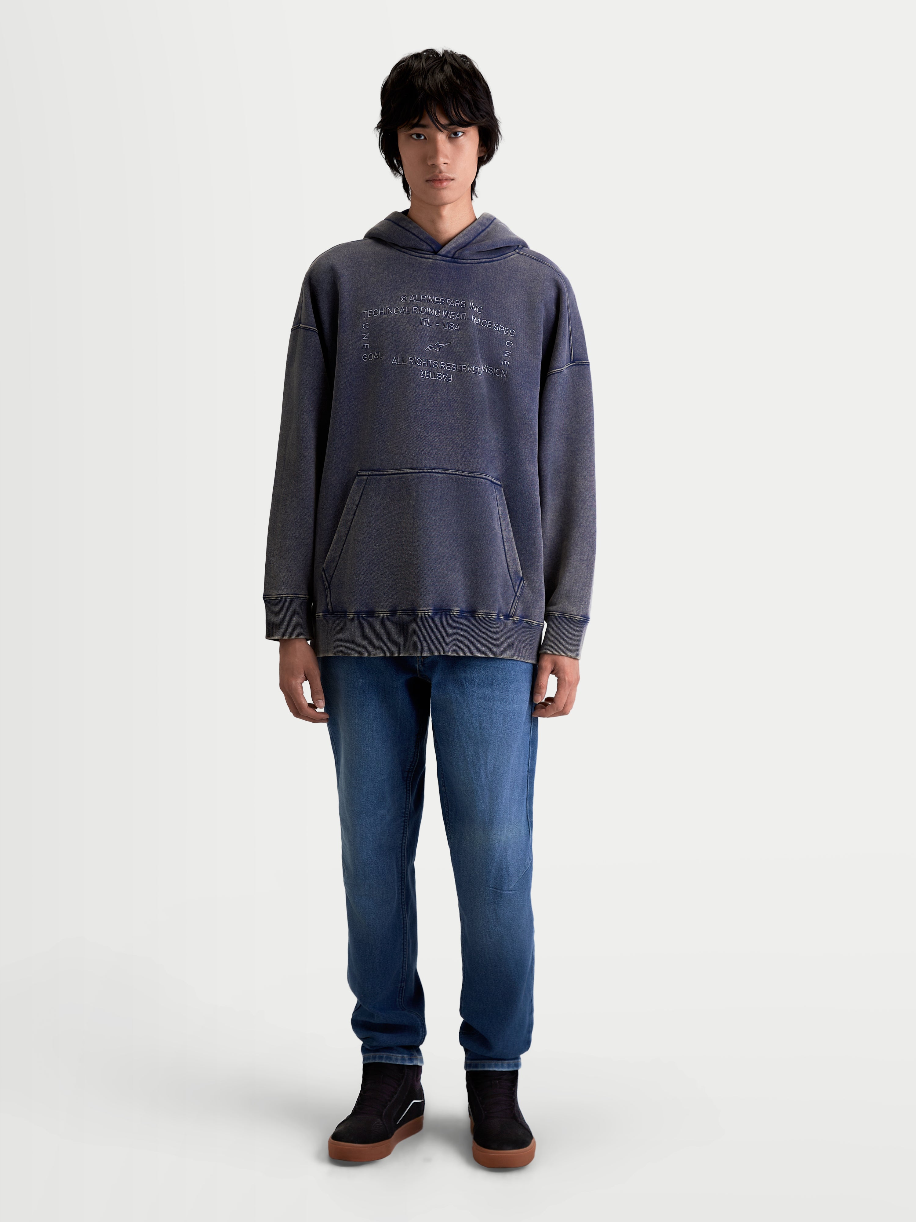 Alpinestars Sweat À Capuche Infinite Washed Oversize, vêtement sportswear pour homme porté par un mannequin, bleu marine délavé avec finition effet neige, doté d'une poche kangourou et du logo Alpinestars brodé sur la poitrine, coupe oversize décontractée en polaire premium.