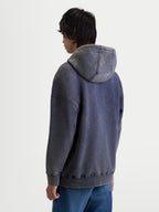 Alpinestars Sweat À Capuche Infinite Washed Oversize, sweat à capuche de sportswear unisexe, bleu marine délavé avec effet neige, vue de dos sur un mannequin montrant la broderie One Goal One Vision sur la capuche et la coupe décontractée en polaire premium.